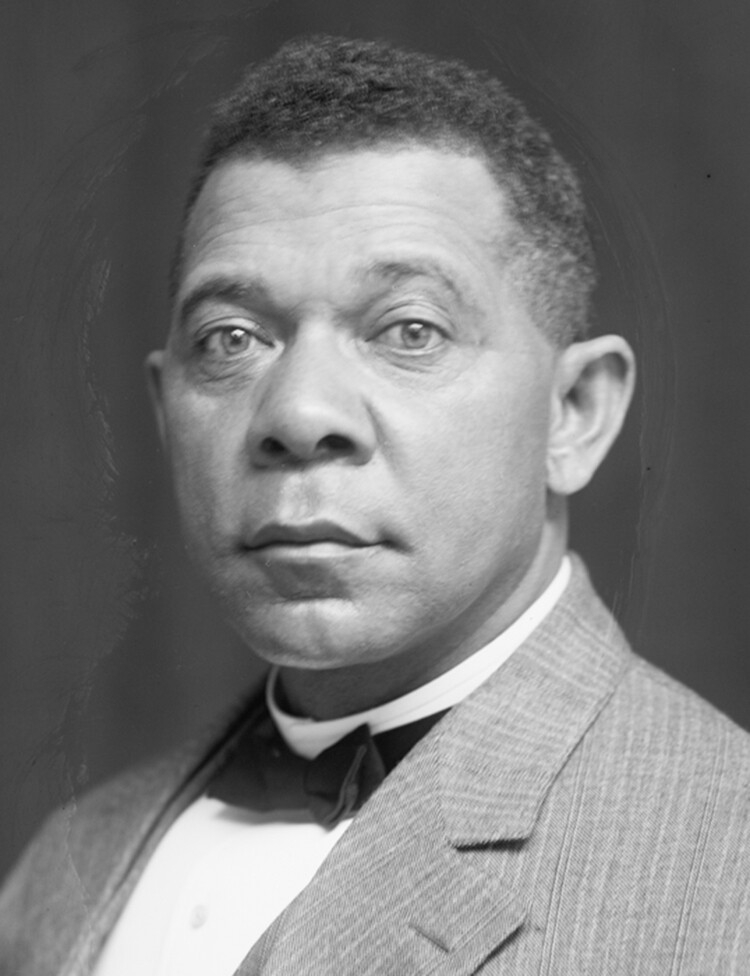 A portrait of Booker T. Washington. He is wearing a light colored suit and a black bow tie.