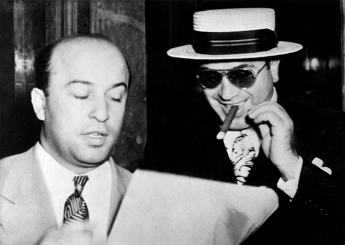 A black-and-white candid photograph of two men wearing suits.