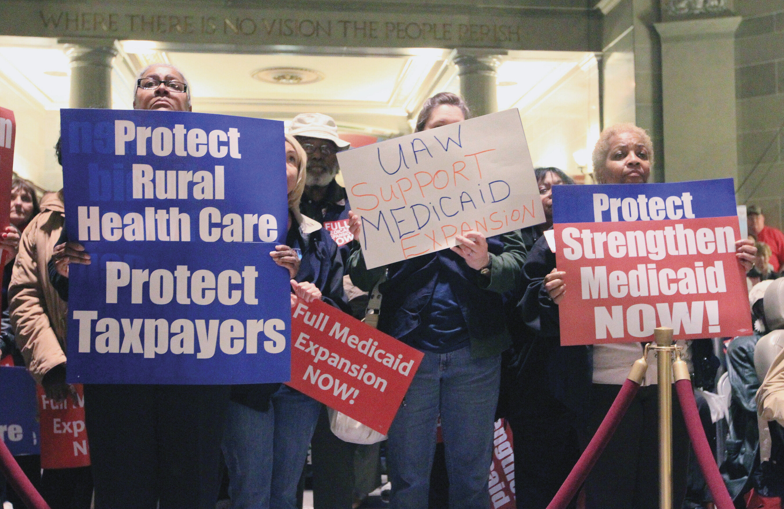 A group of protestors hold signs in favor of Medicaid.