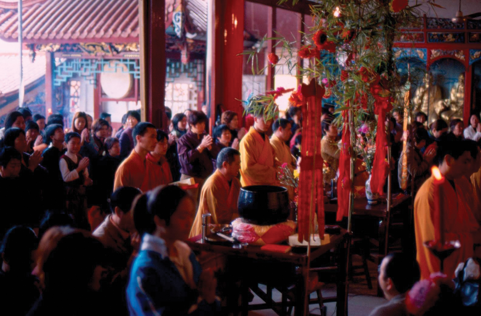 Crowds of people gather to worship with Buddist monks in a temple.