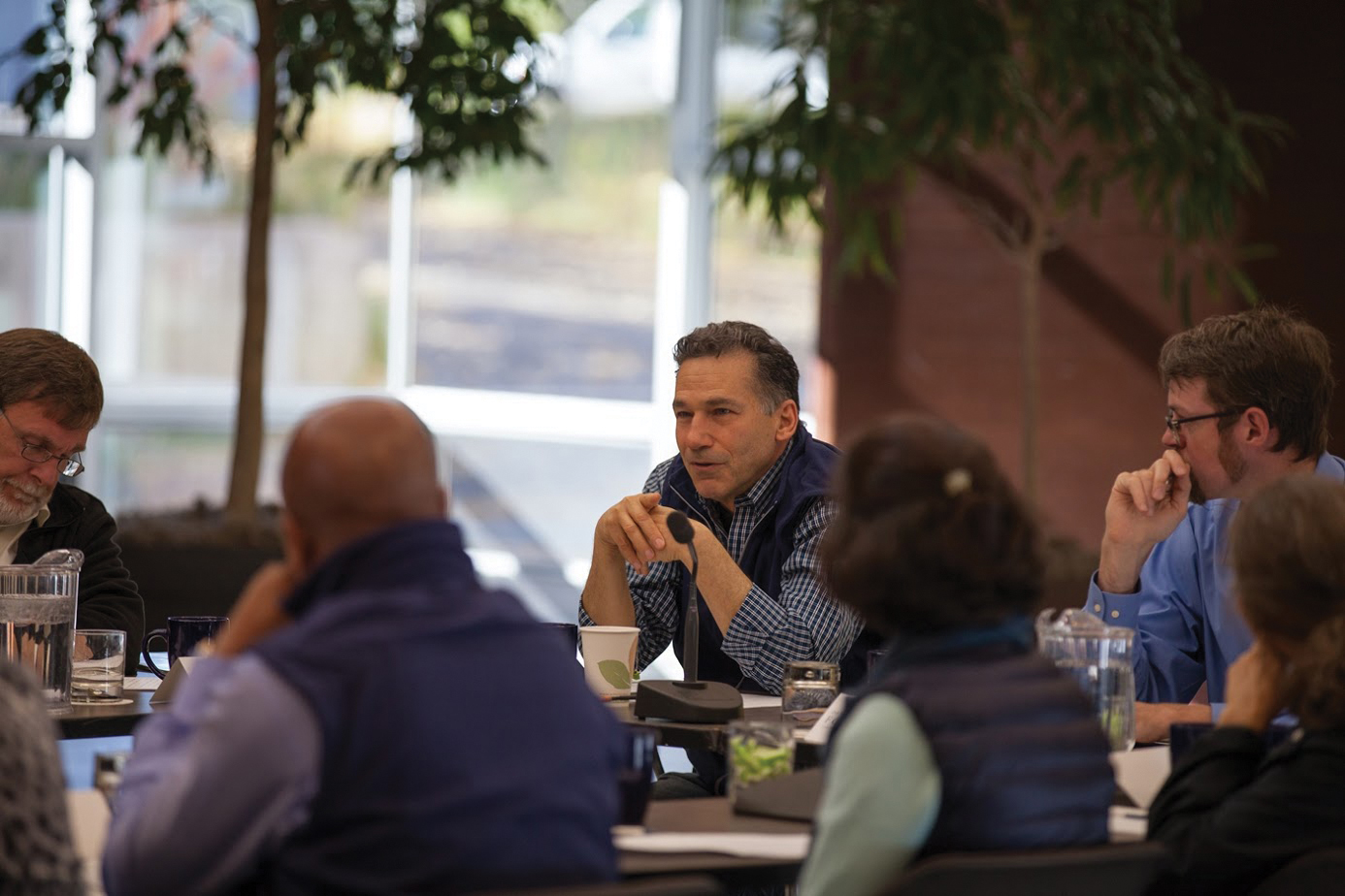 People in business casual attire sit around a table having a discussion.