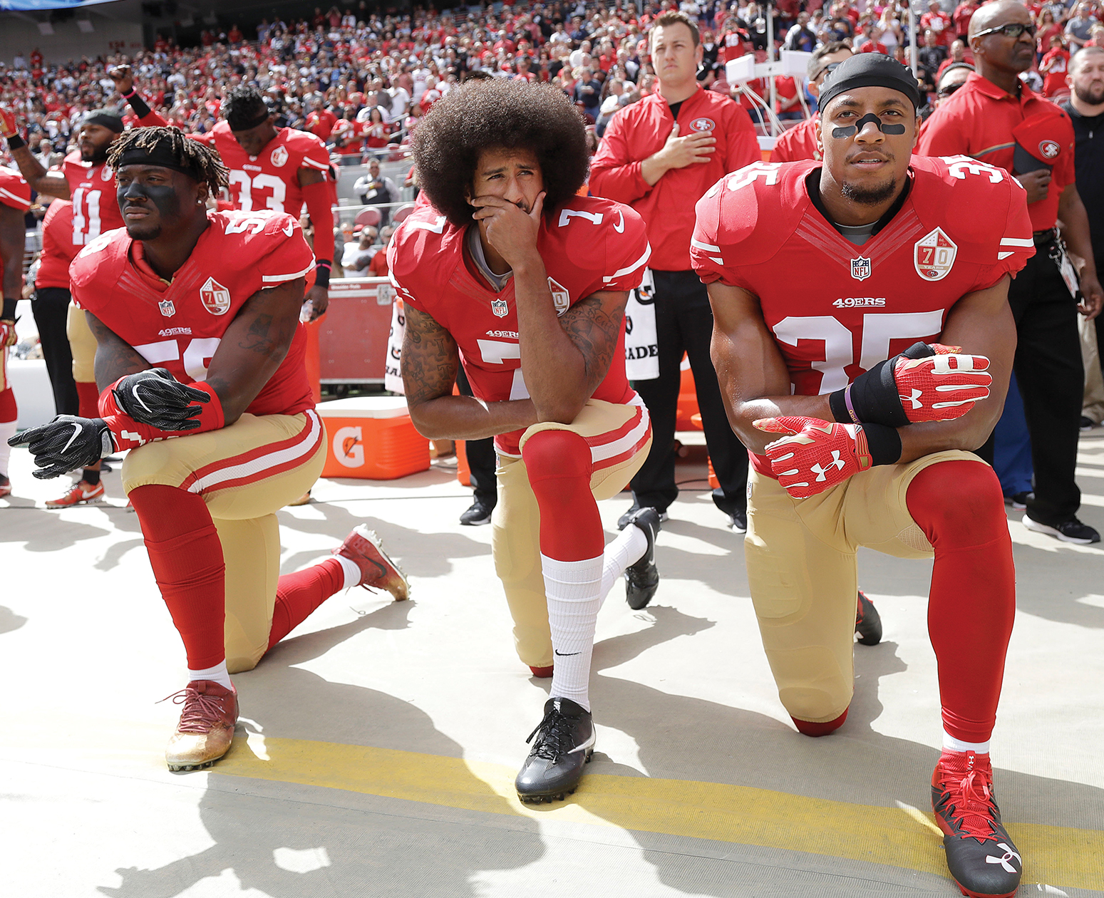 NFL players kneel in uniform during the National Anthem.