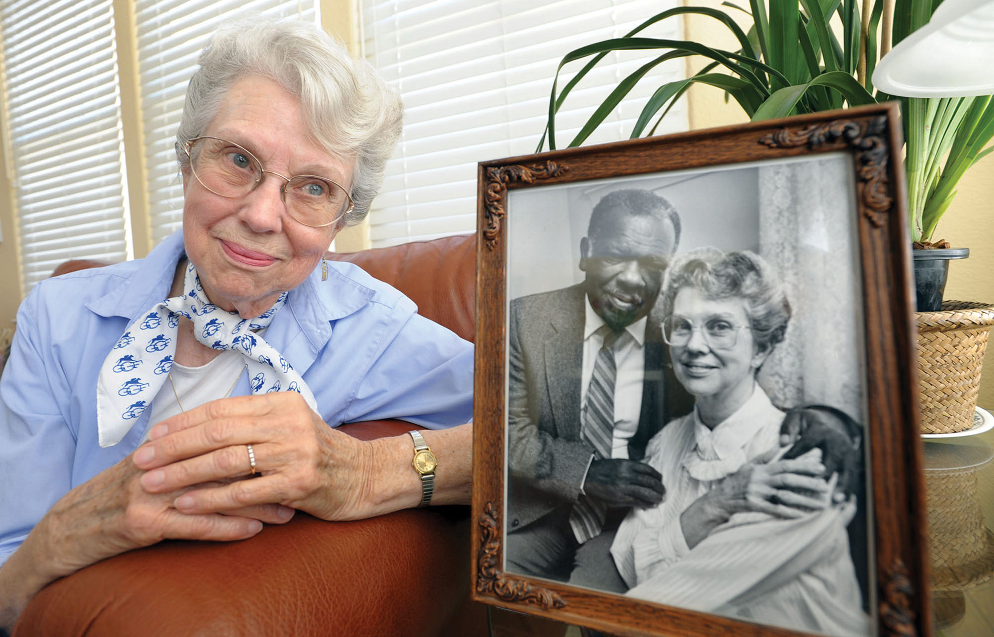 A white woman sits on a couch looking at a picture of her and a Black man.