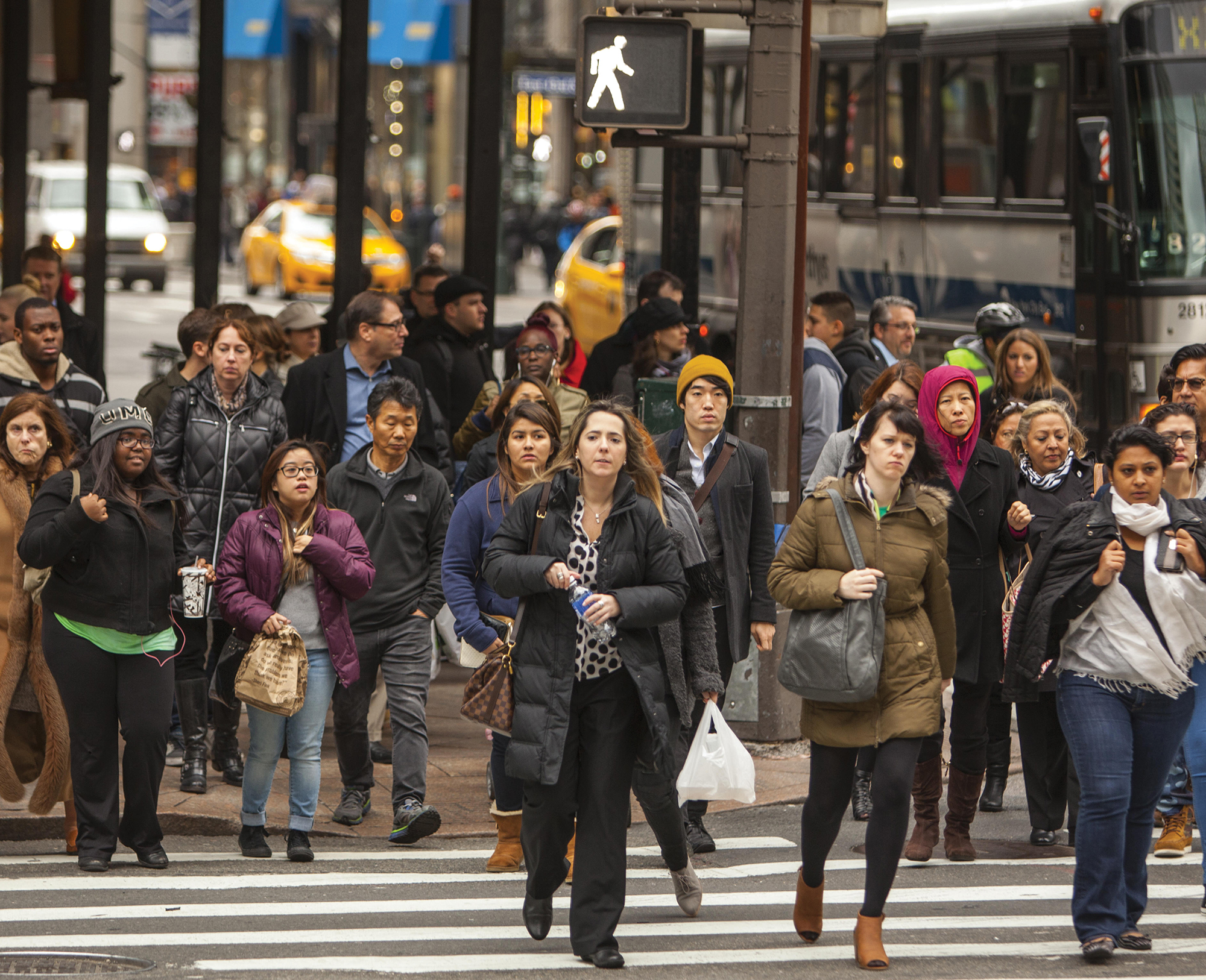 A large group of pedestrians cross a crosswalk.