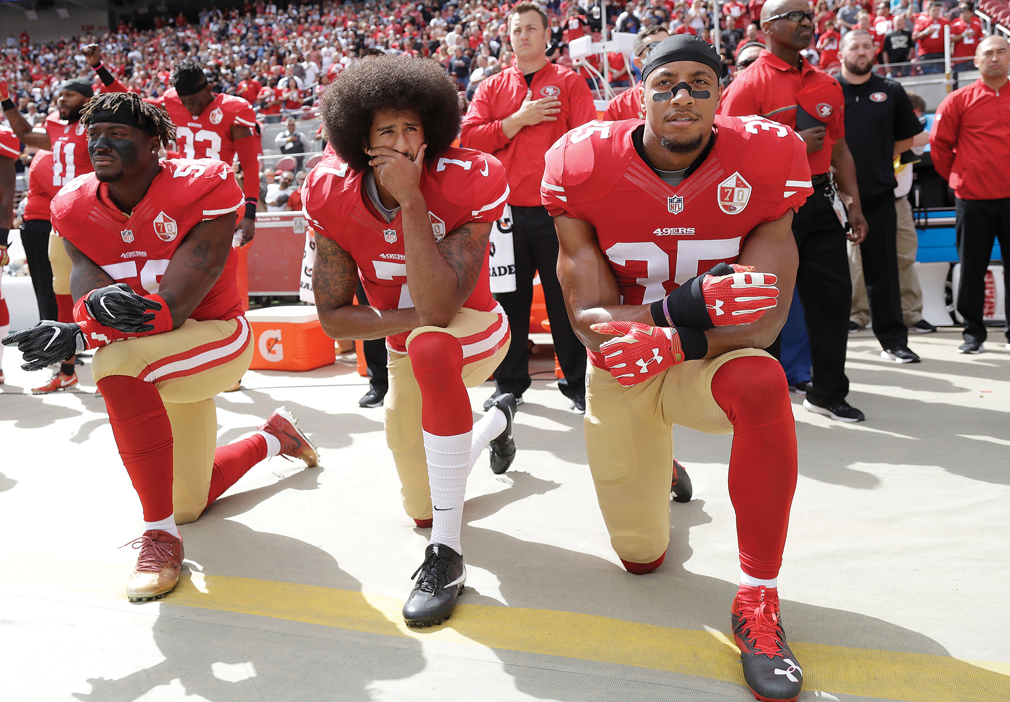 NFL players kneel in uniform during the National Anthem.