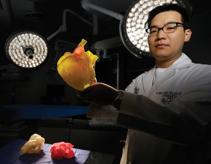 A man wearing a lab coat holding a model of a human heart.
