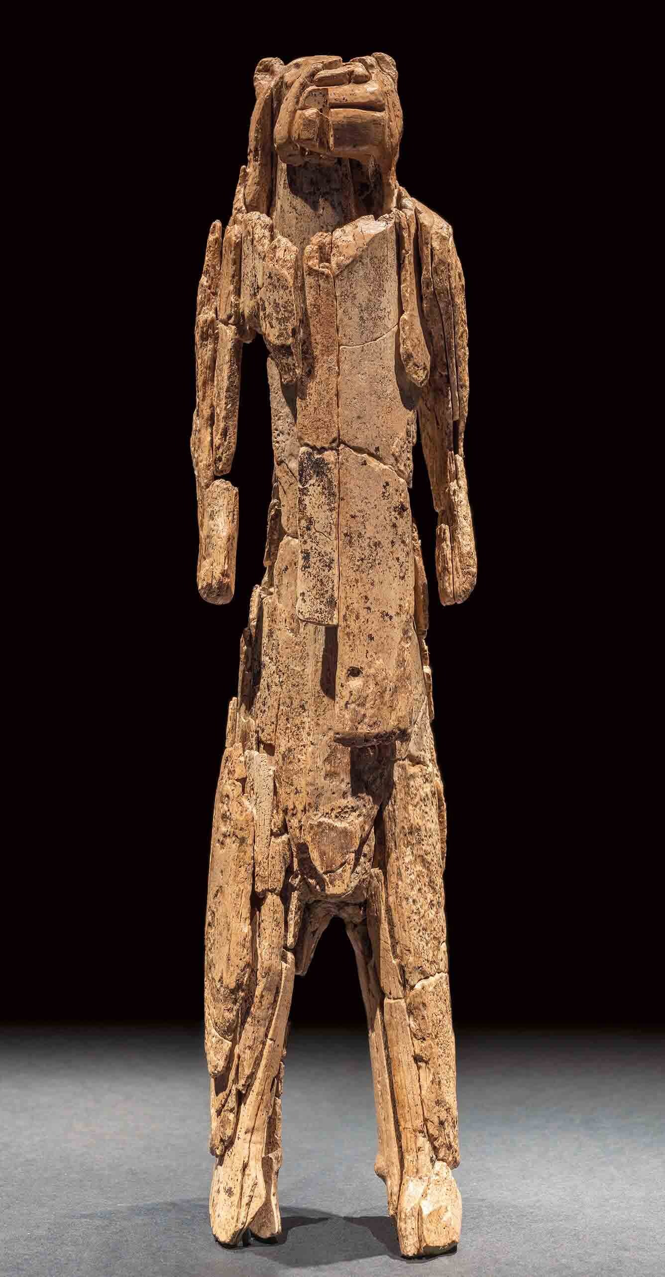 Figure made of pale brown organic material, standing upright on two legs.