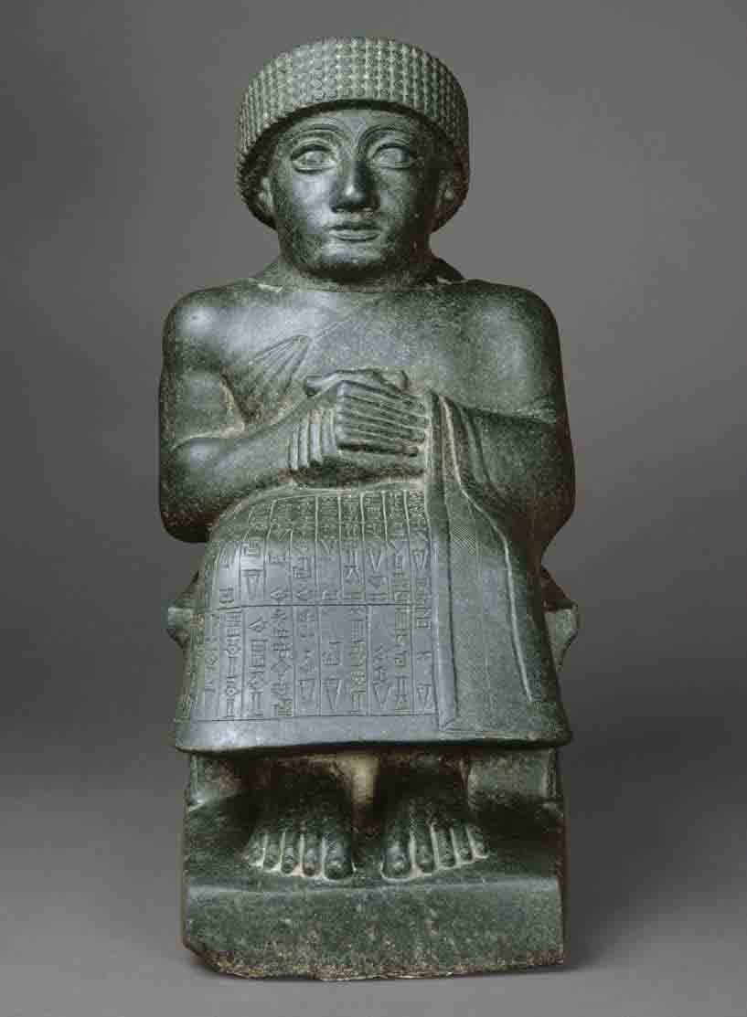 A seated figure, sculpted of dark stone.