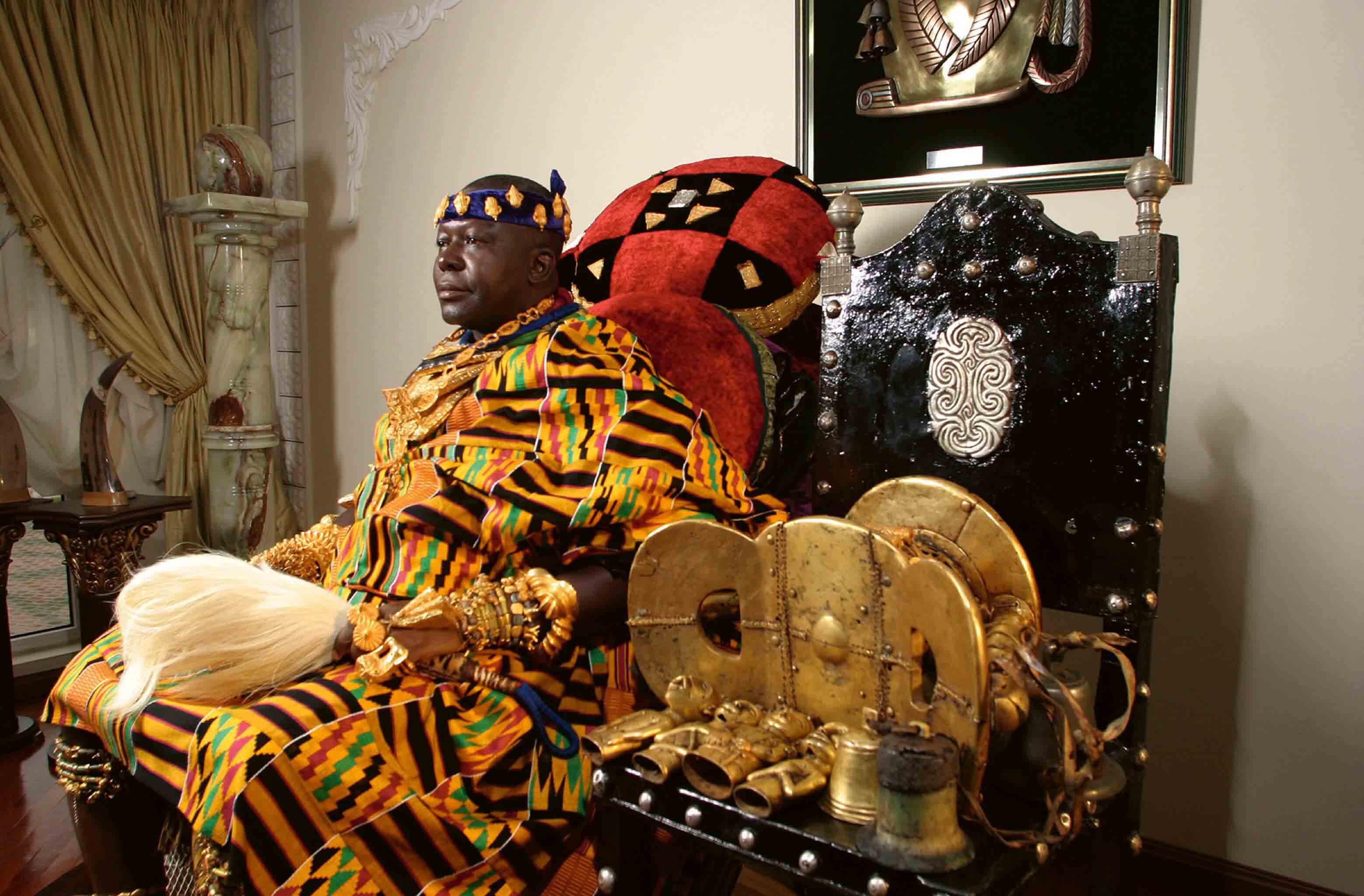 Color photograph of a king and a sacred object beside him.