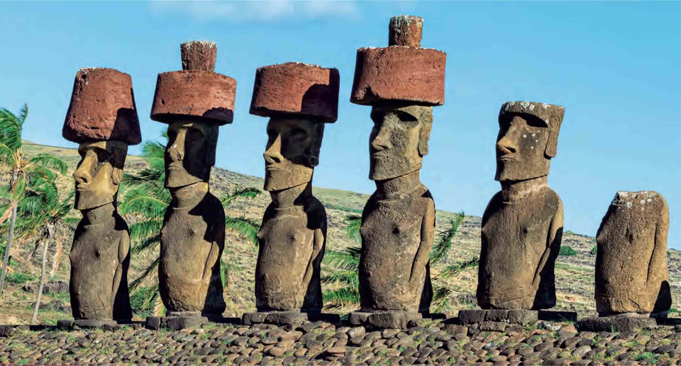 Six massive stone statues, standing in a row on a common platform.