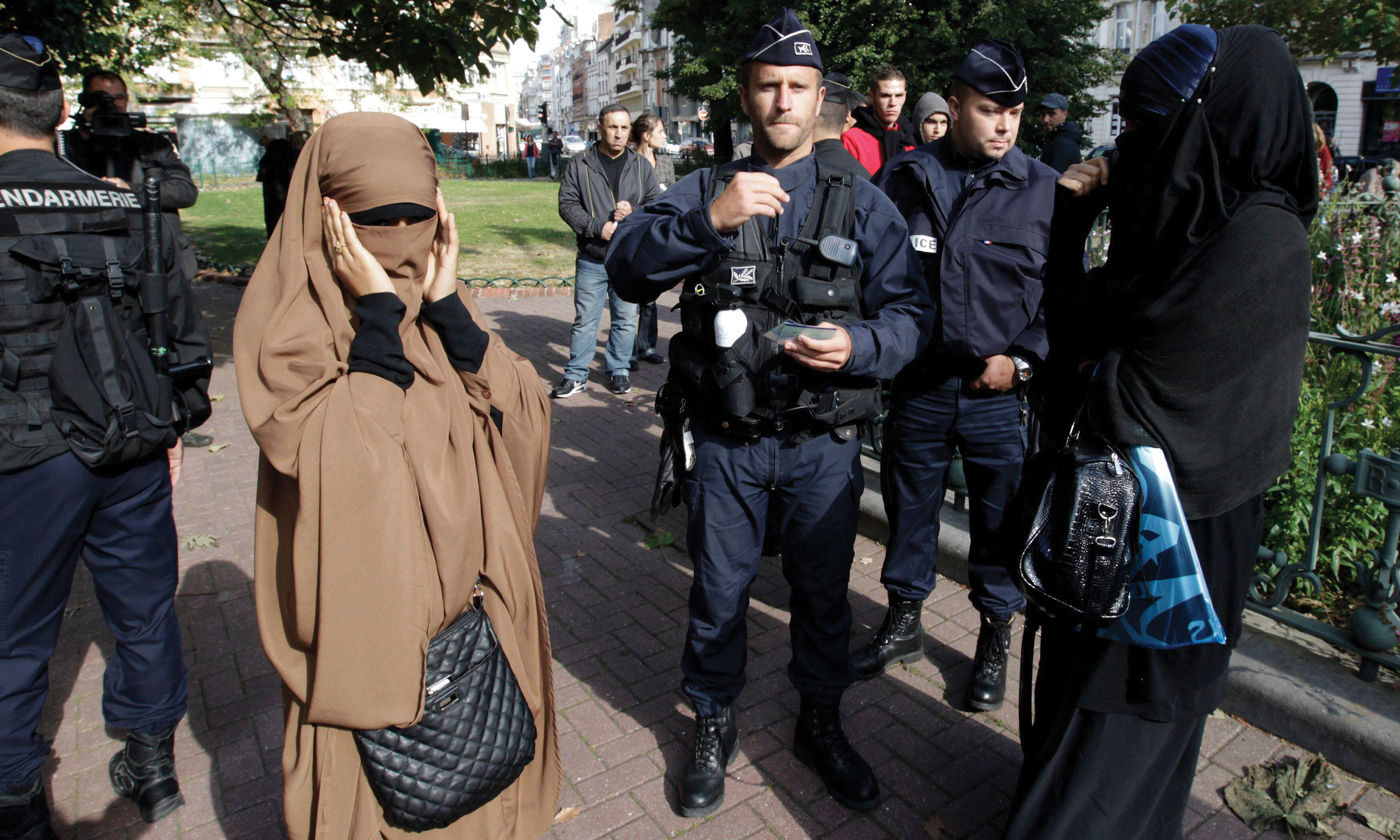 French police detaining two women wearing full-face veils in public.