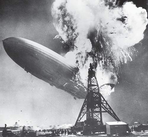 A black-and-white photo shows Hindenburg, a commercial passenger airship, going up in flames mid-air.