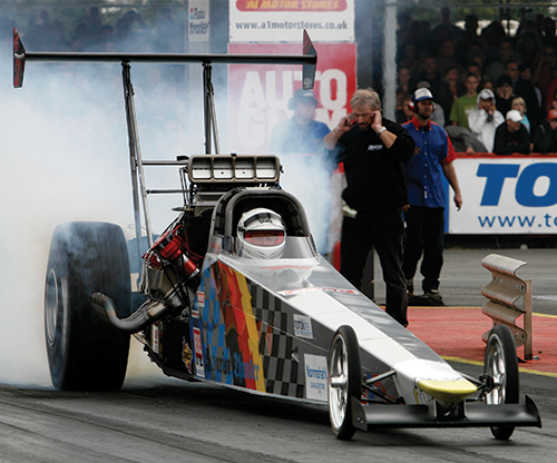 A photo shows a Formula One car emitting smoke on a racetrack.