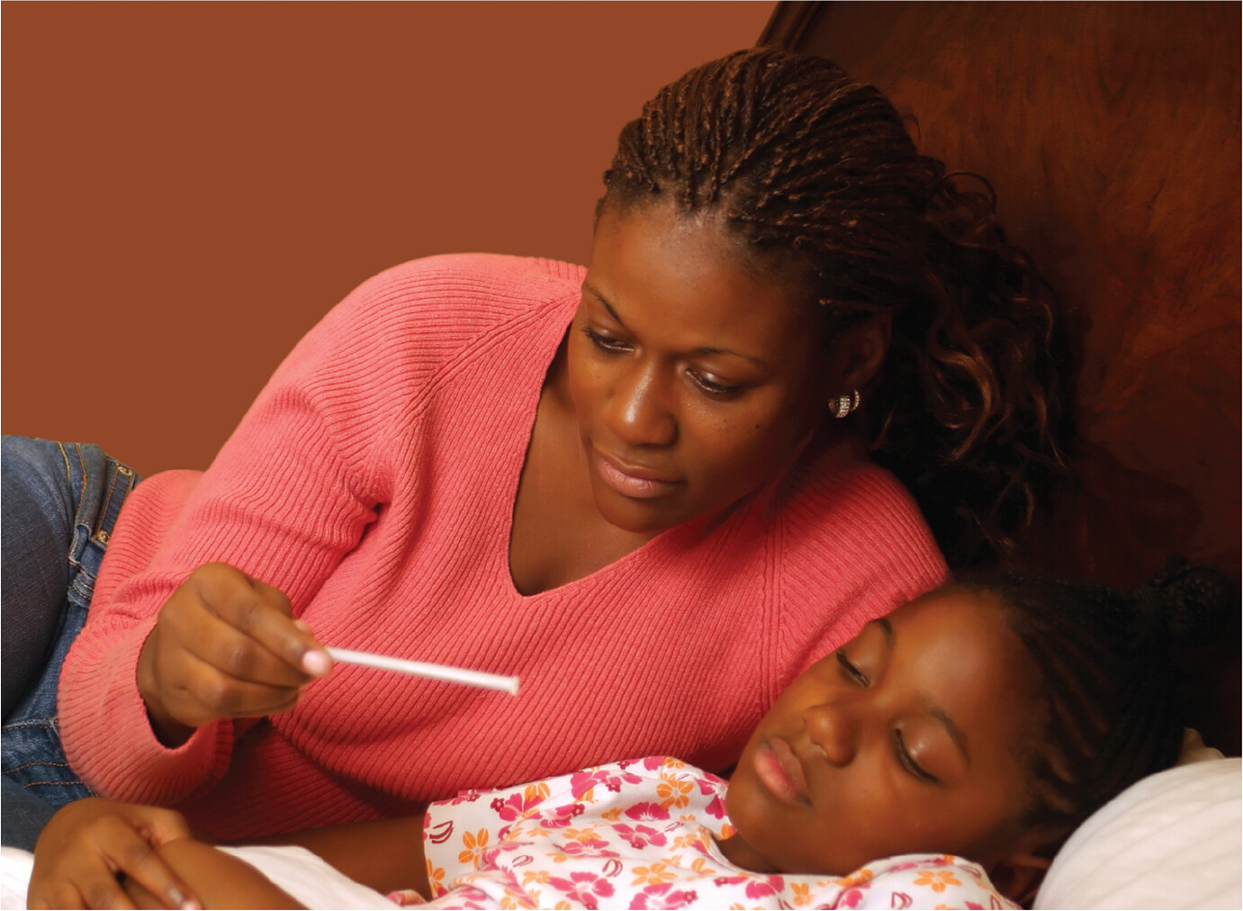 A photo of a woman checking the temperature of a child.