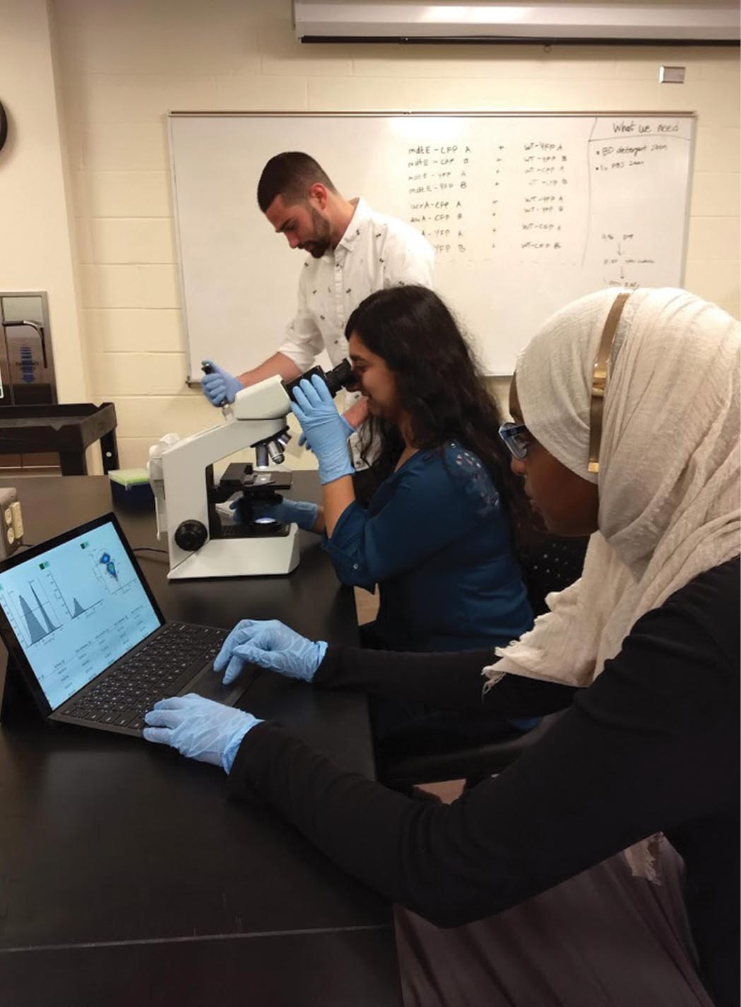 A photo shows two women and a man in a research room.