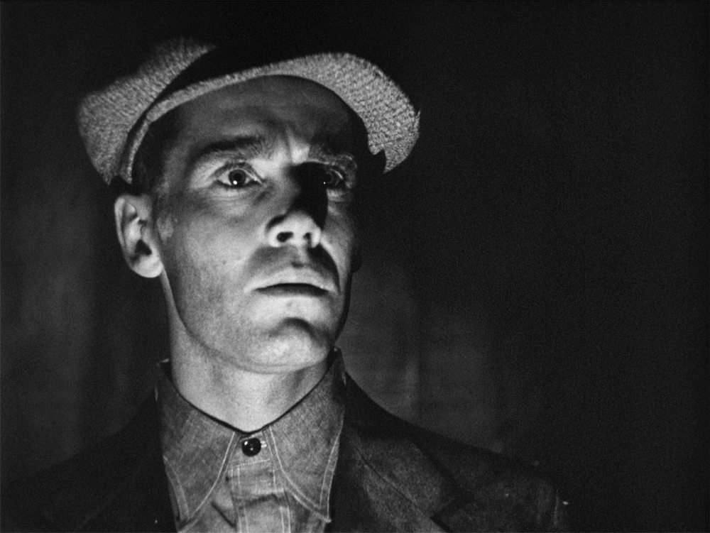 In The Grapes of Wrath, candlelight illuminates a portion of a man’s face.