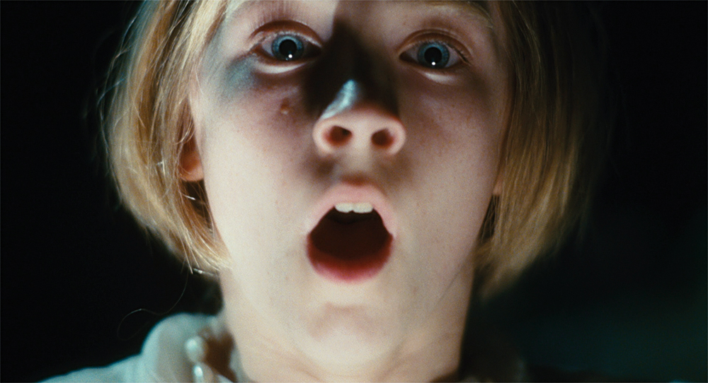 A girls with her mouth open and eyes wide in Atonement.