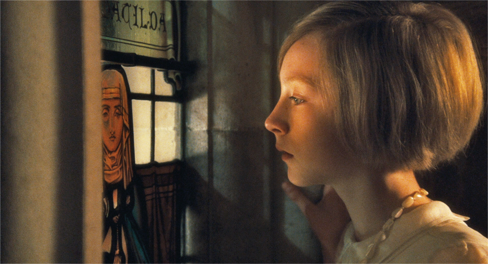 A girl looks out of a clear pane of a stain-glass window in Atonement.