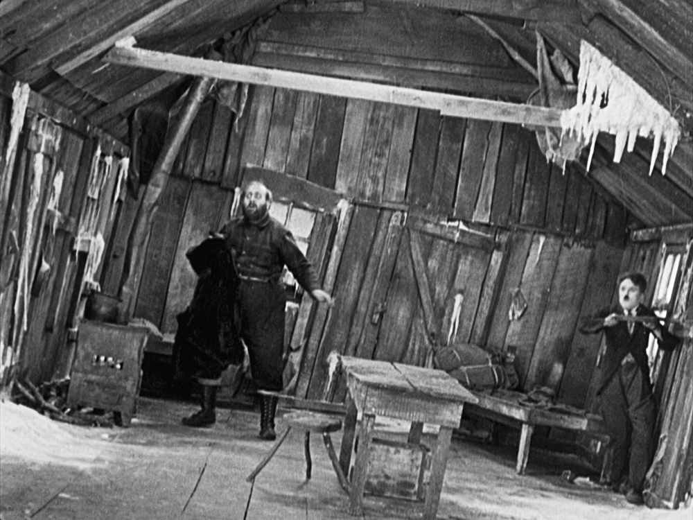 Two men slip as the cabin tips to one side in The Gold Rush.