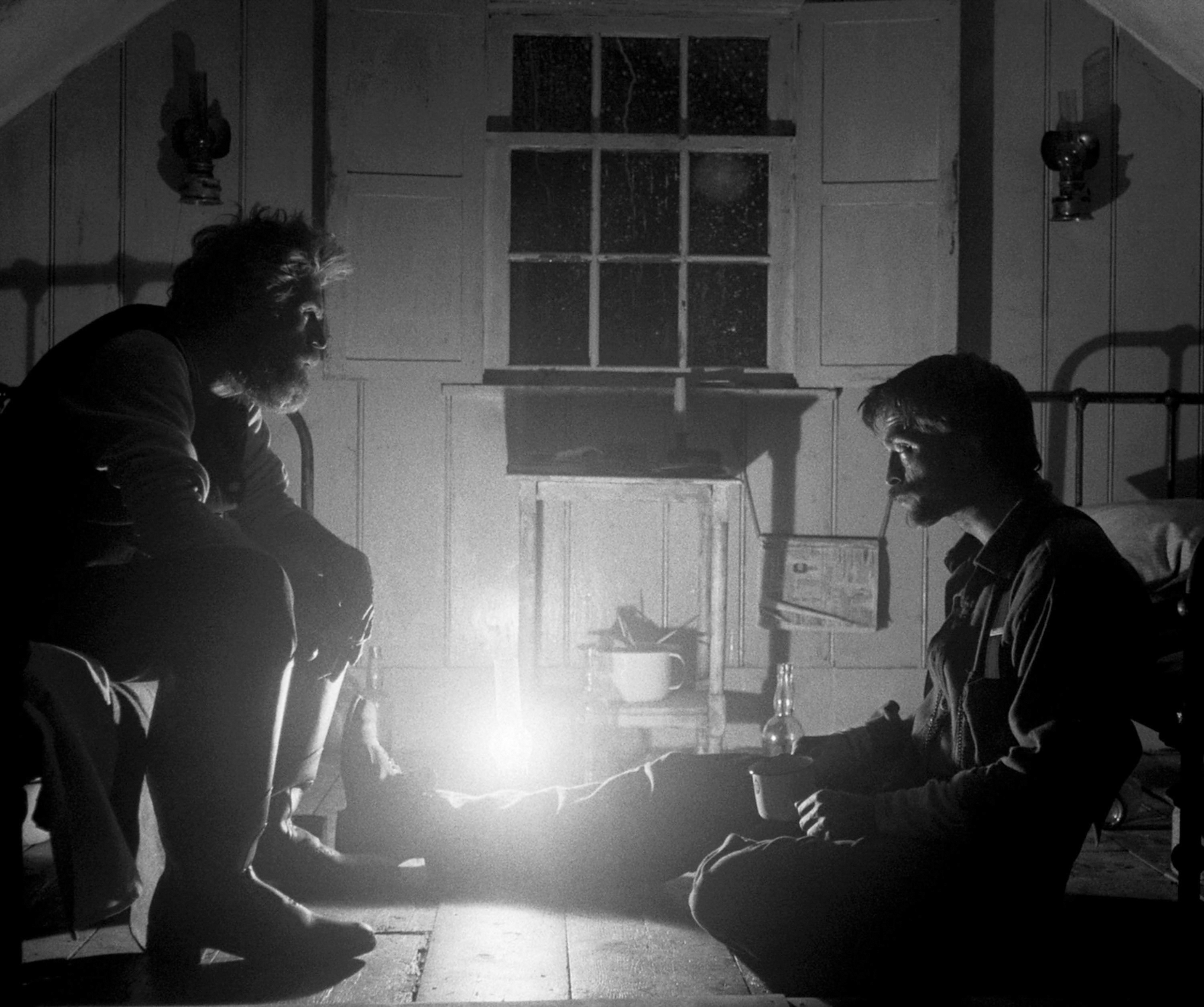 In The Lighthouse, Thomas Wake and Thomas Howard are shown face-to-face in dim black and white lighting.