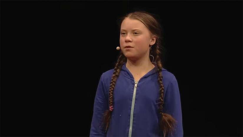 A screenshot of Greta Thunberg speaking on stage.
