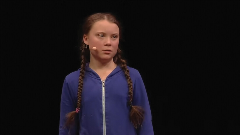 A screenshot of Greta Thunberg speaking on stage.