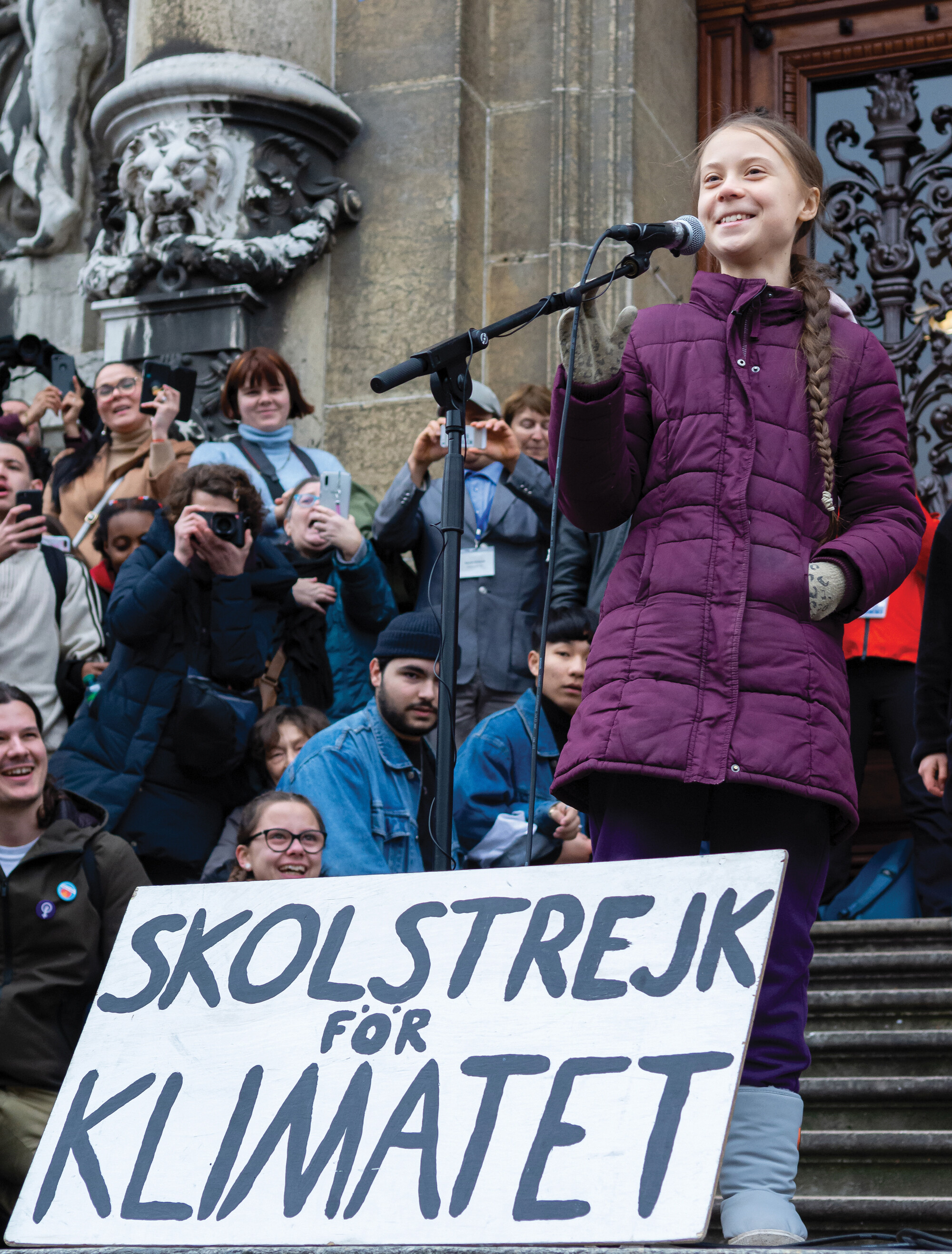 Greta Thunberg speaking into a microphone in front of a crowd.