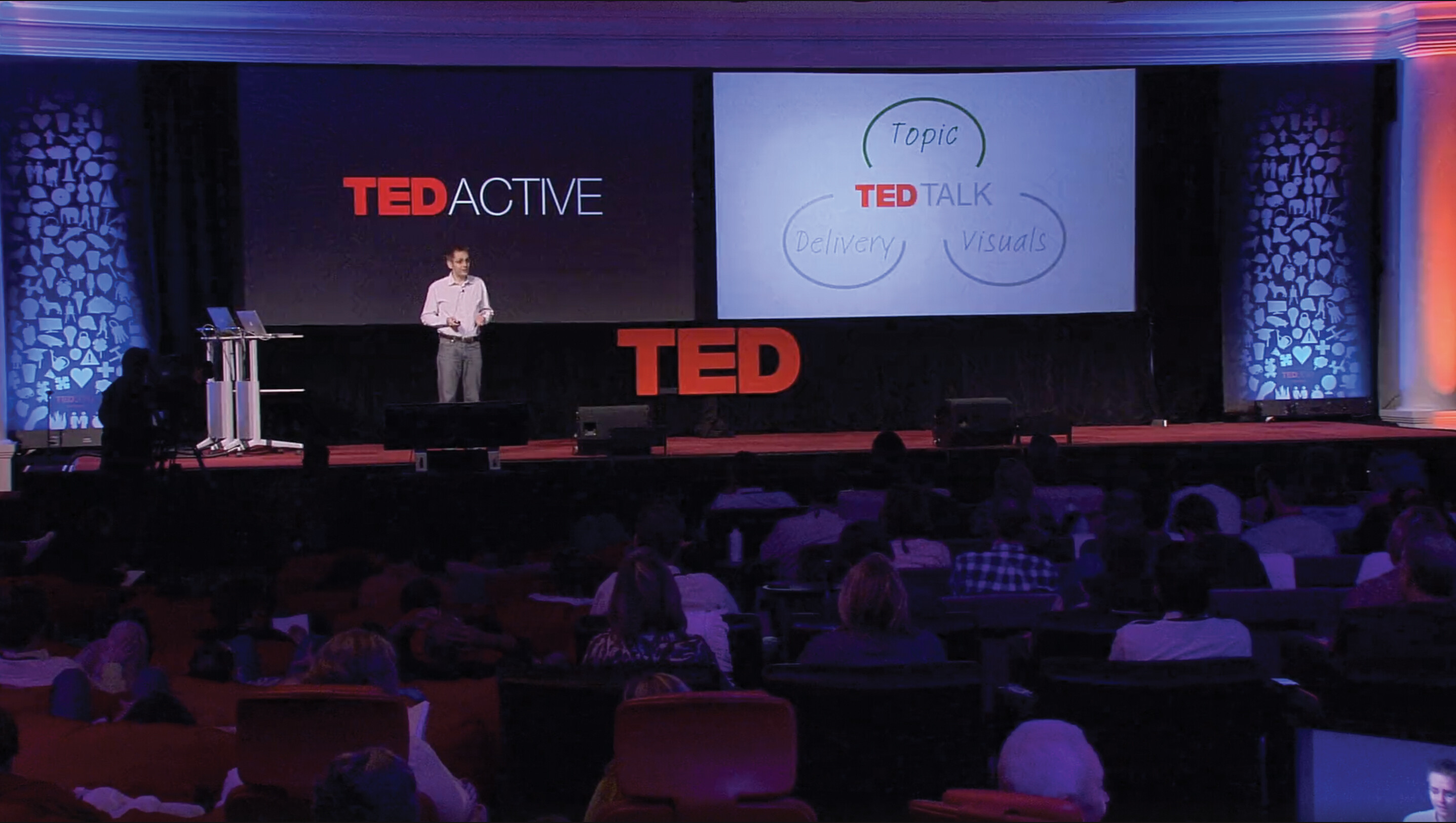 A screenshot of Sebastian Wernicke’s Ted X talk. He stands on a stage in an auditorium in front of a large crowd.