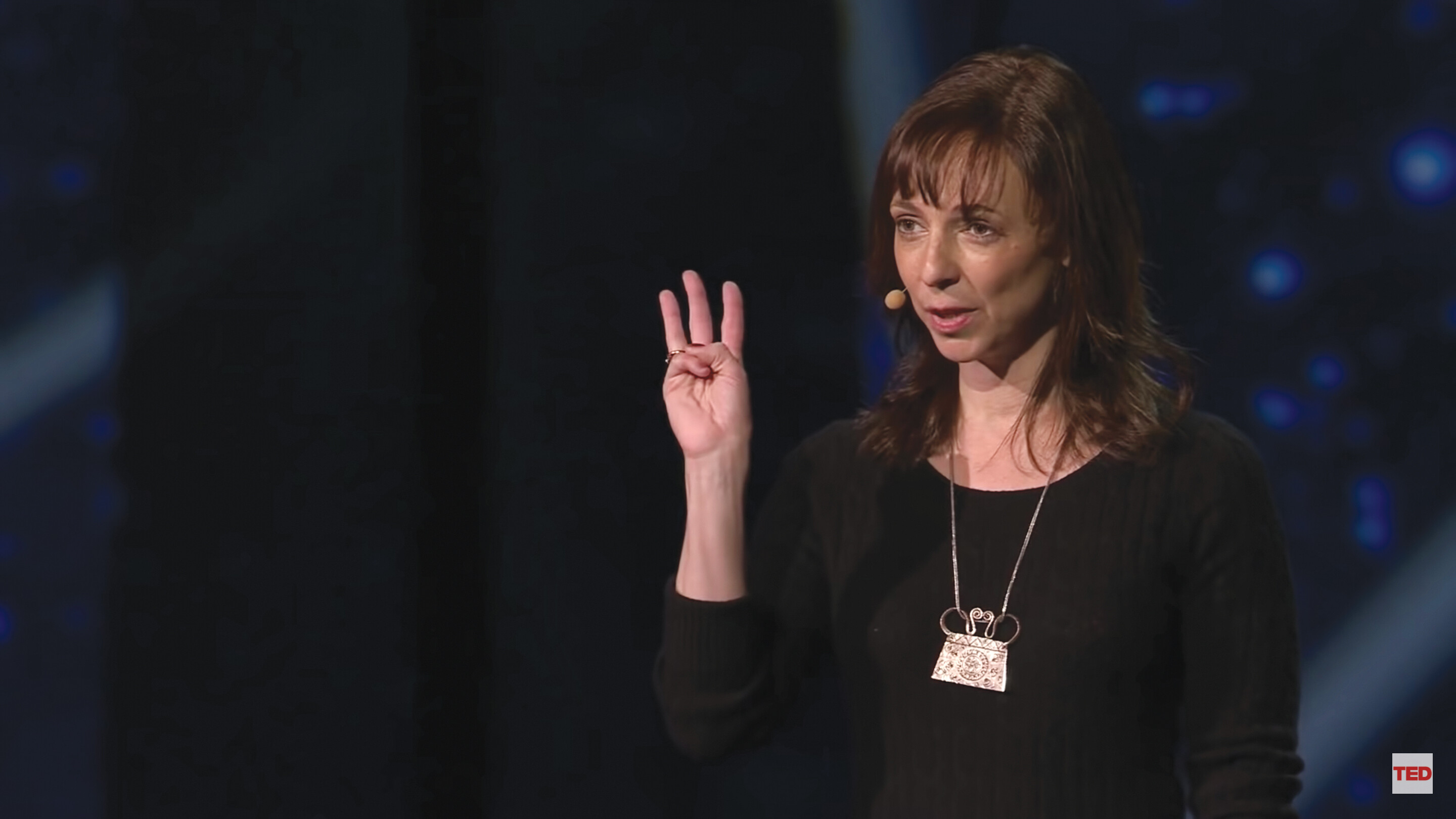 A screenshot of Susan Cain’s TED talk. She stands on a stage in an auditorium.