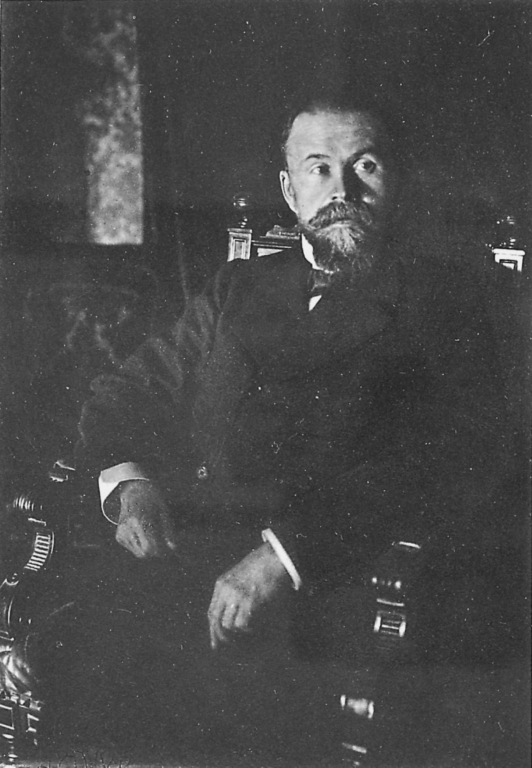 A bearded man sits in a chair and poses for a picture.