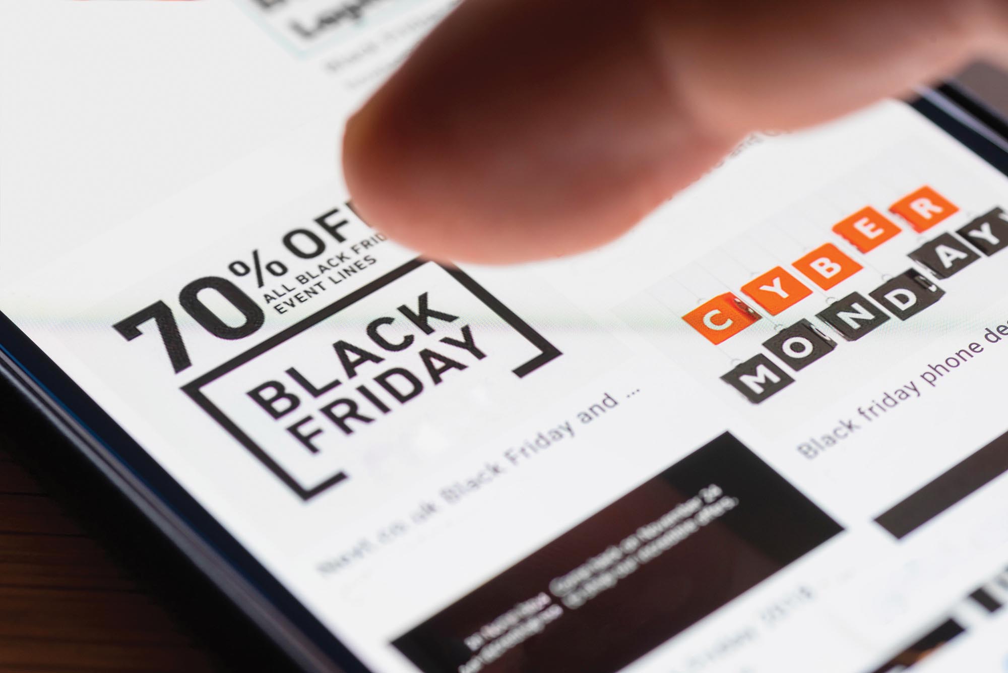 A persons finger hovering over an advertisement on a screen that says 70 percent off all Black Friday event lines.