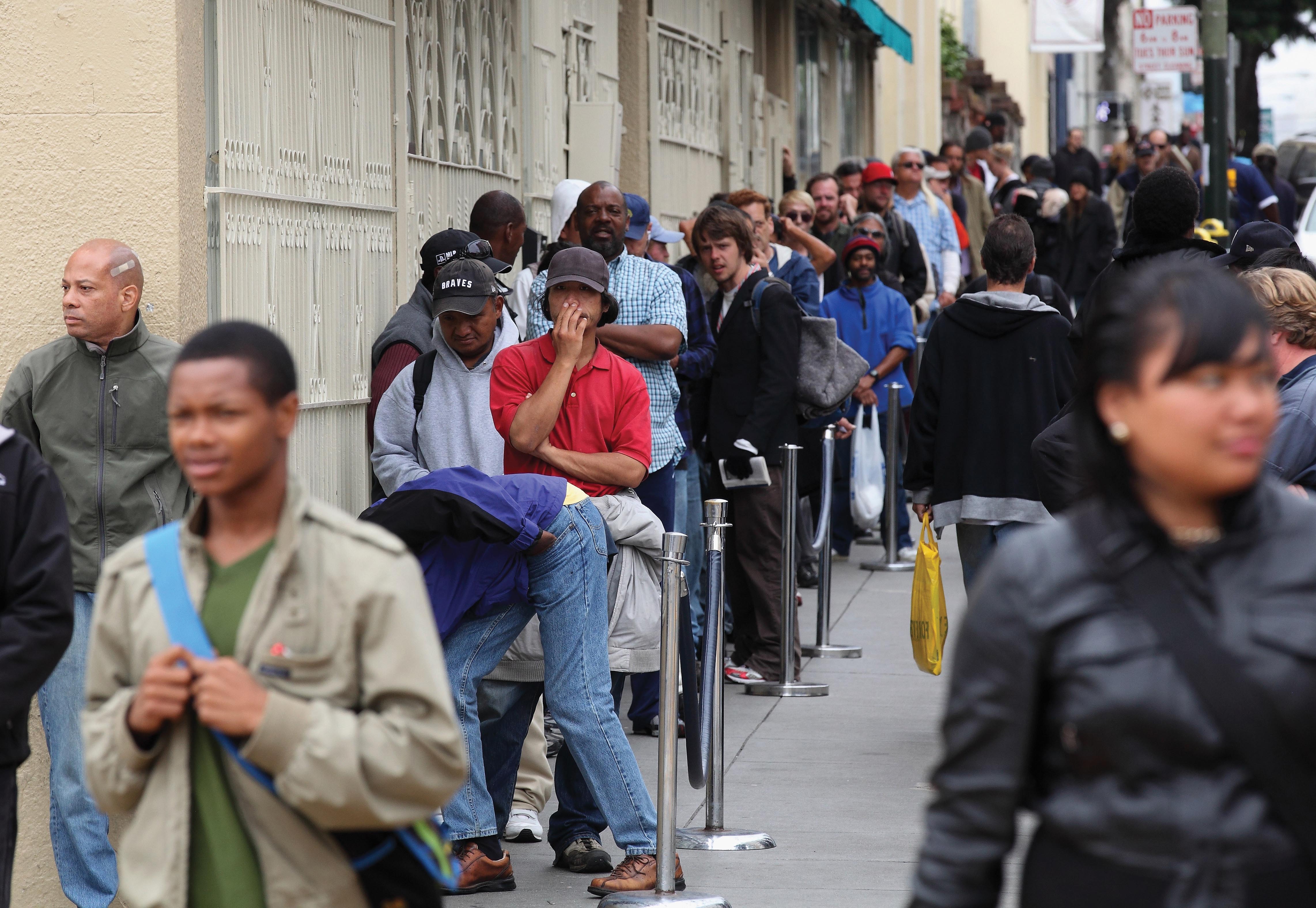 People waiting in line on a sidewalk.