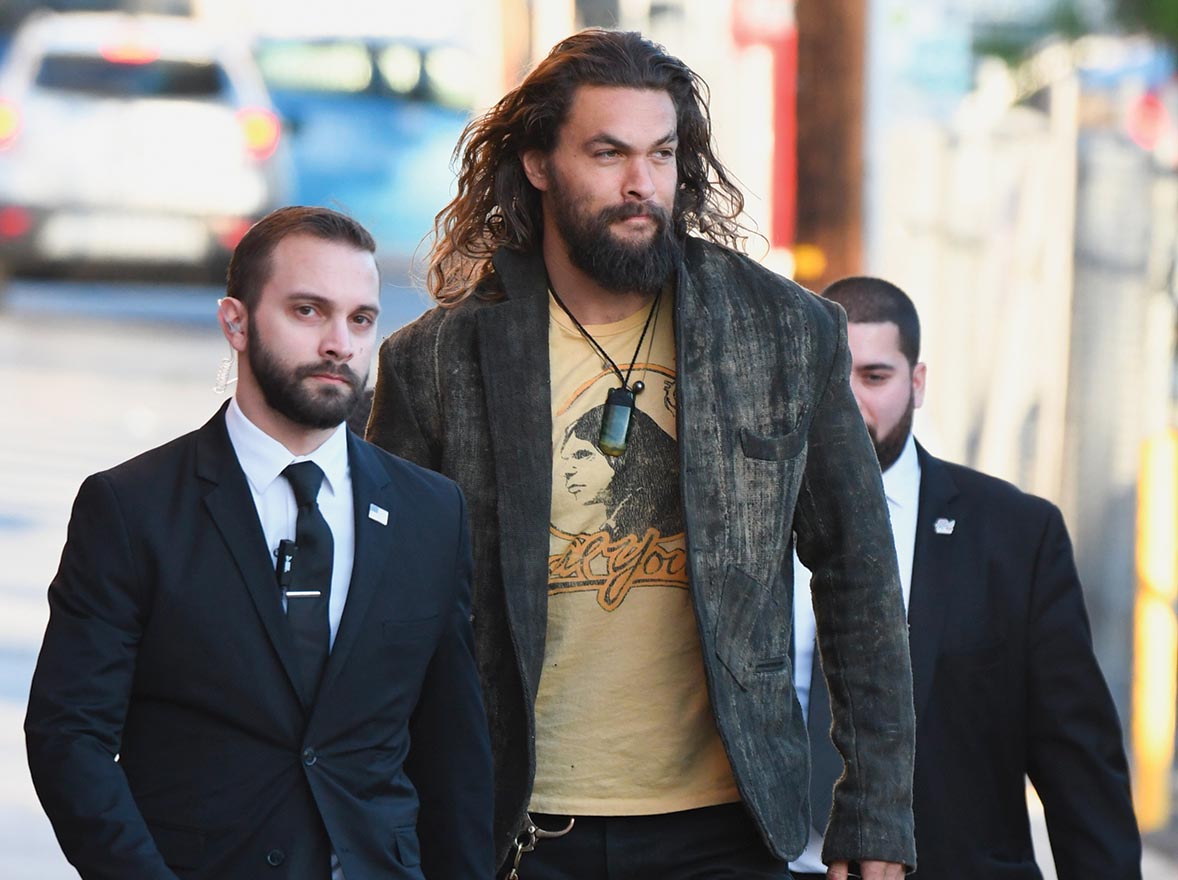 Jason Momoa flanked by two bodyguards.