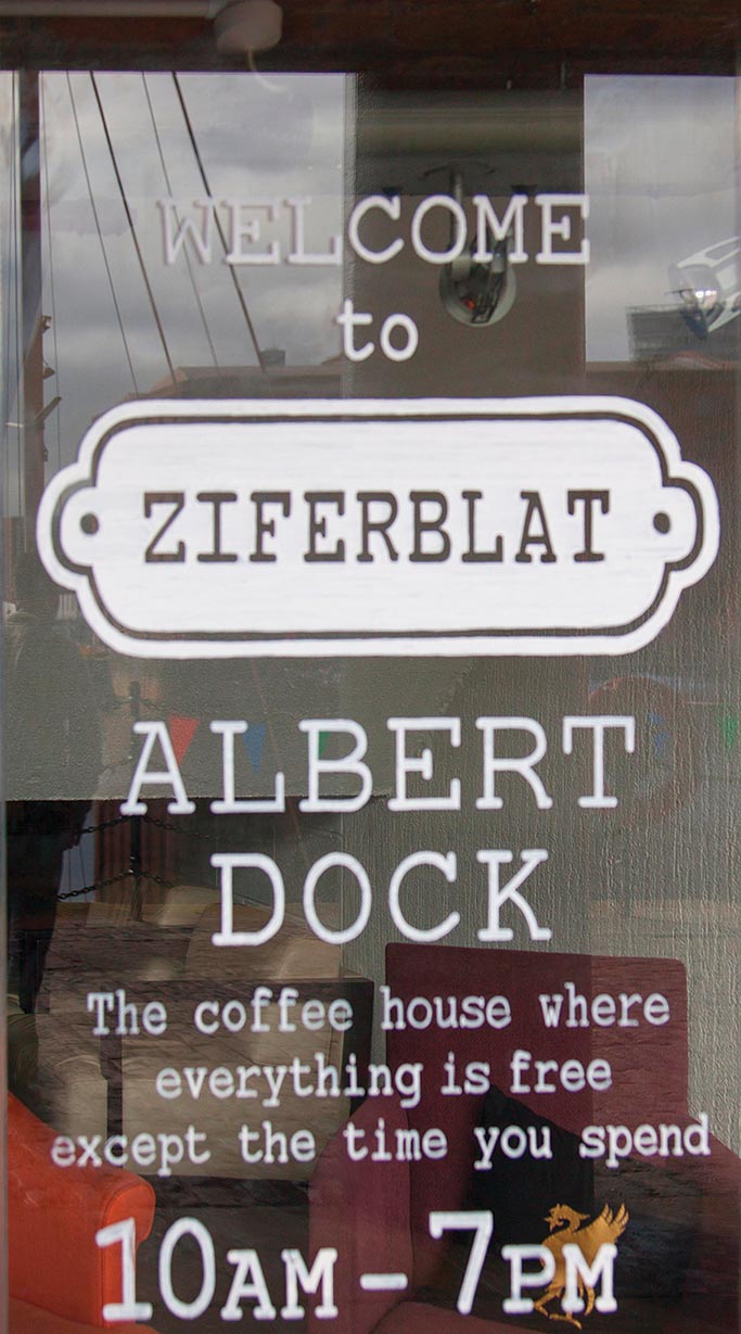 A painted sign on a glass window, welcoming people to Ziferblat.
