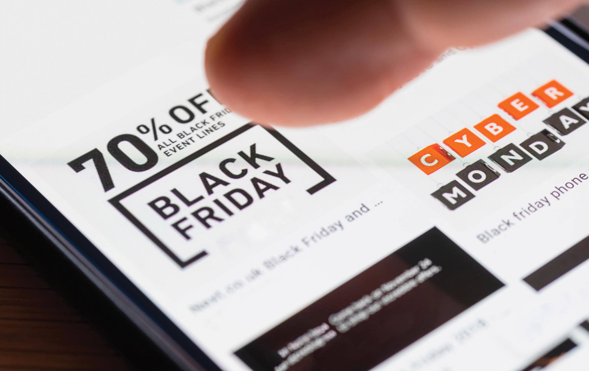 A person’s finger hovering over an advertisement on a screen that says 70 percent off all Black Friday event lines.
