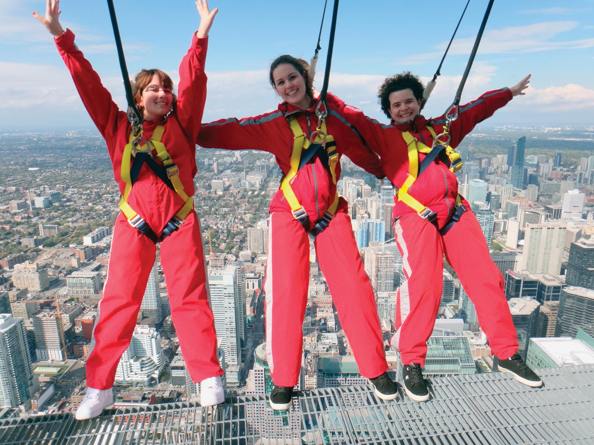 People in safety harnesses leaning off the top of a tall building.