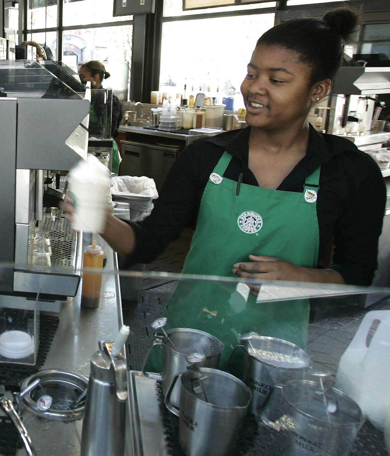 A Starbucks employee making a coffee drink.