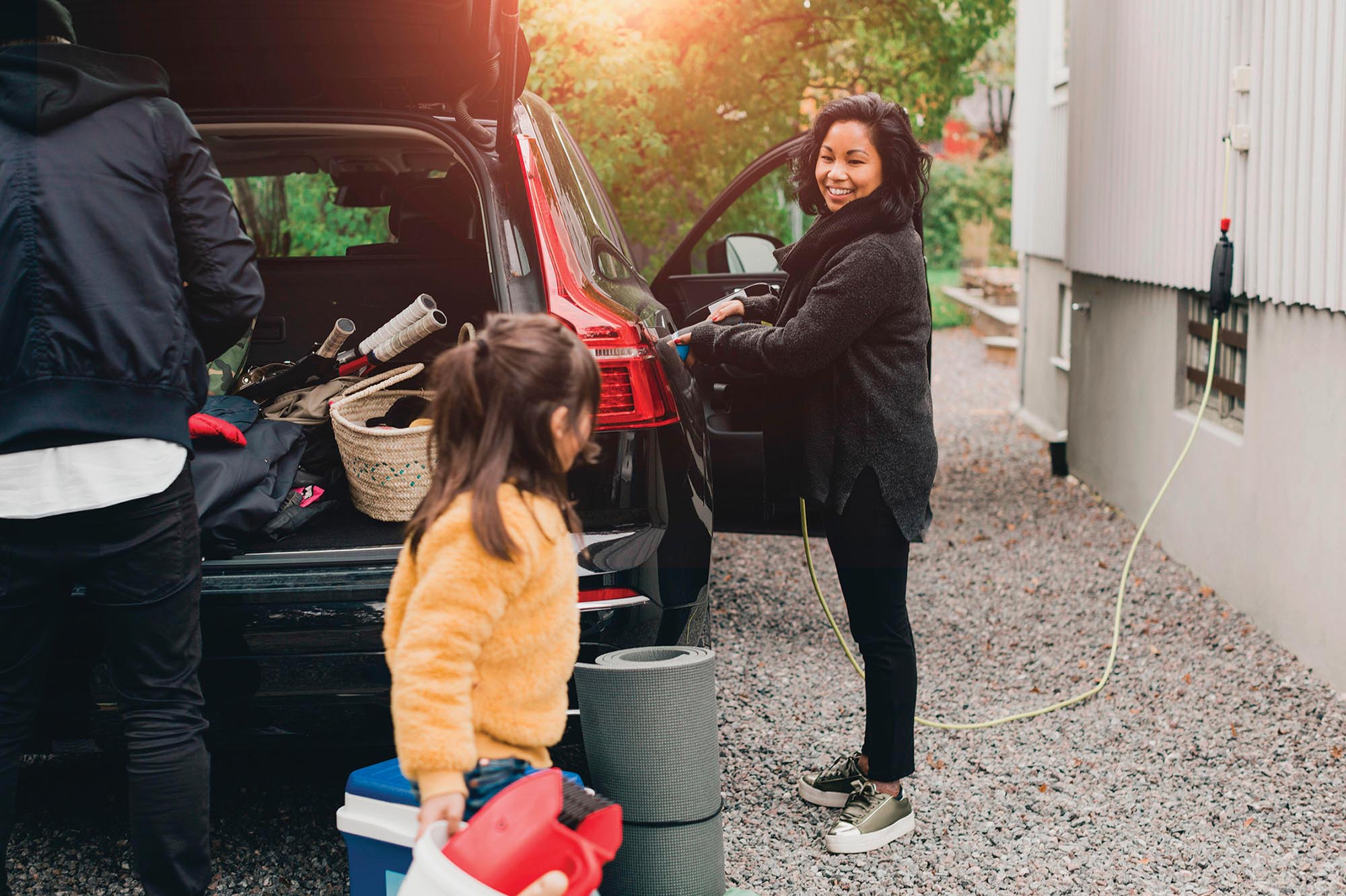 A smiling woman charges up her family’s S U V.