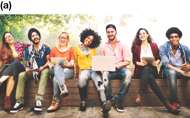 A group of students sitting in a row on an outdoor retaining wall.