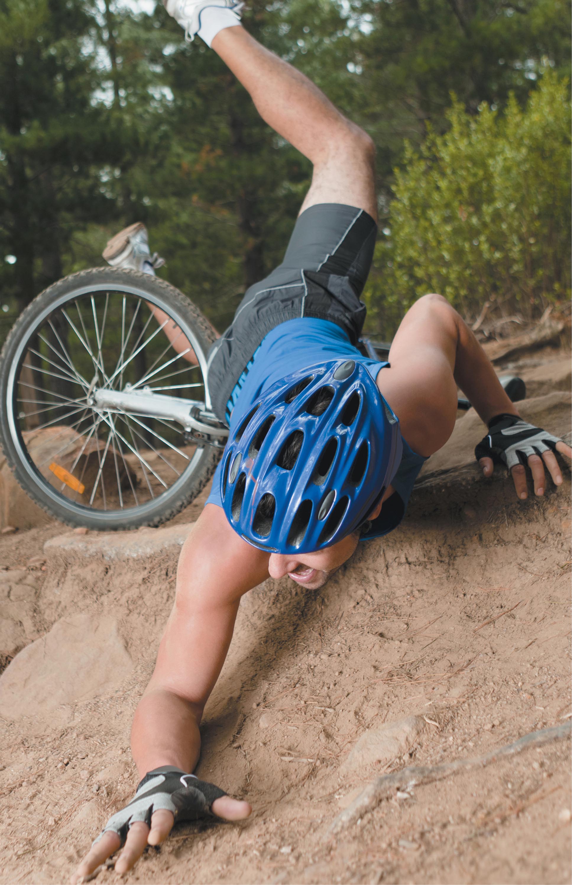 A photo depicting a person falling off of their bike outside.