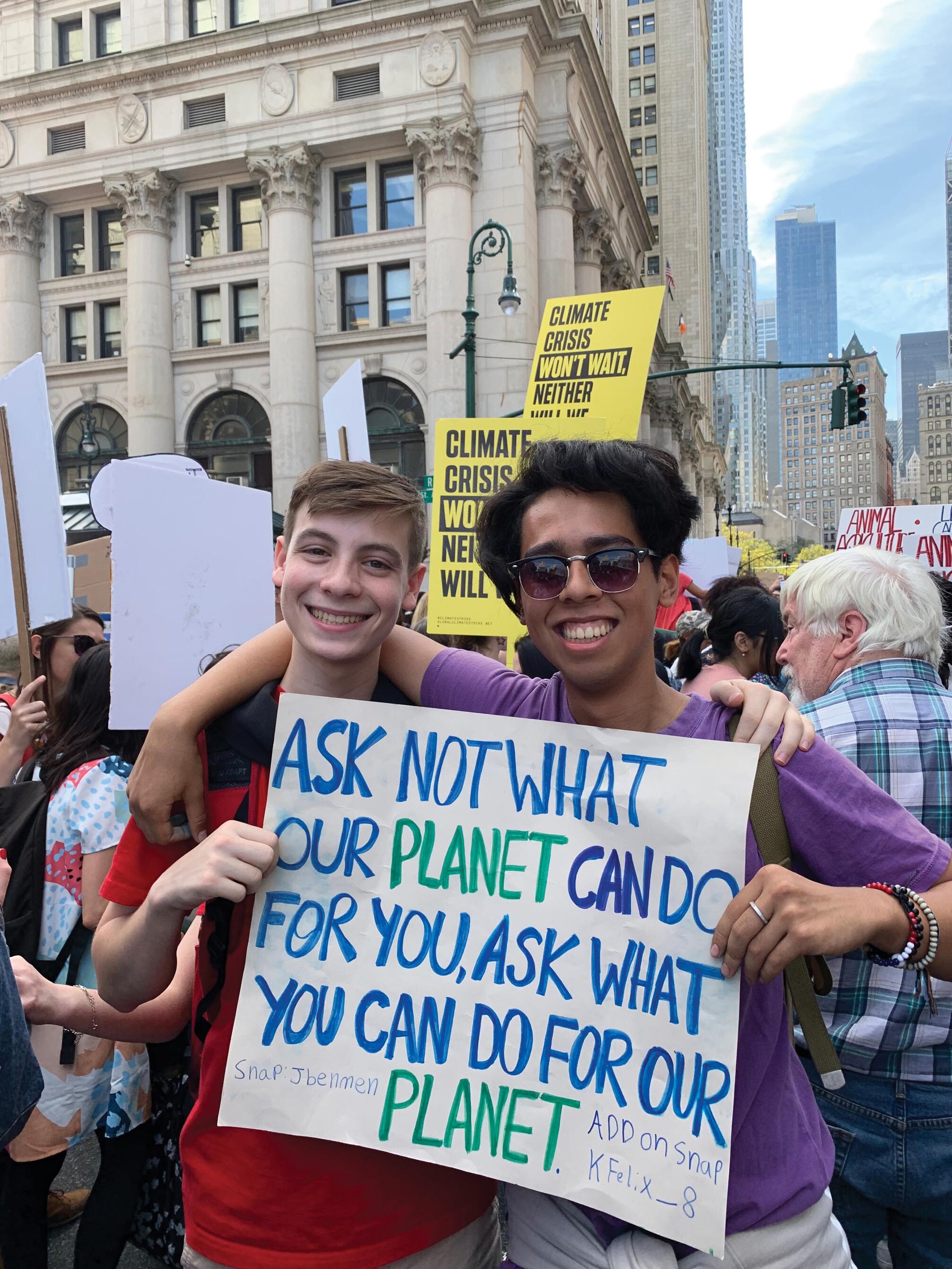 A photo of two young boys standing on a road with a chart, near a large crowd.