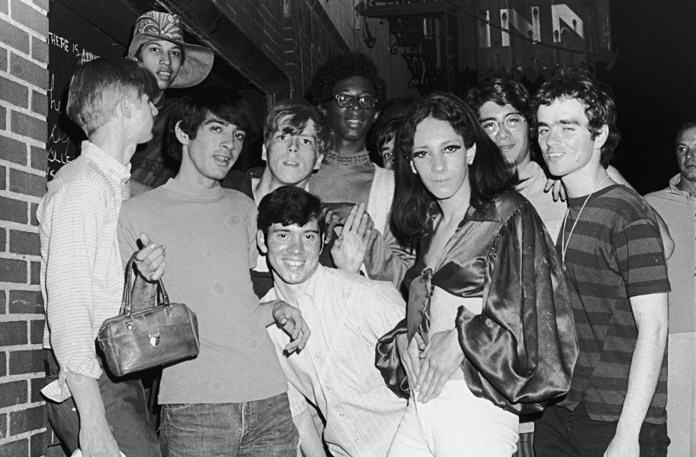 A photo shows a group of young people posing in front of the Stonewall Inn.