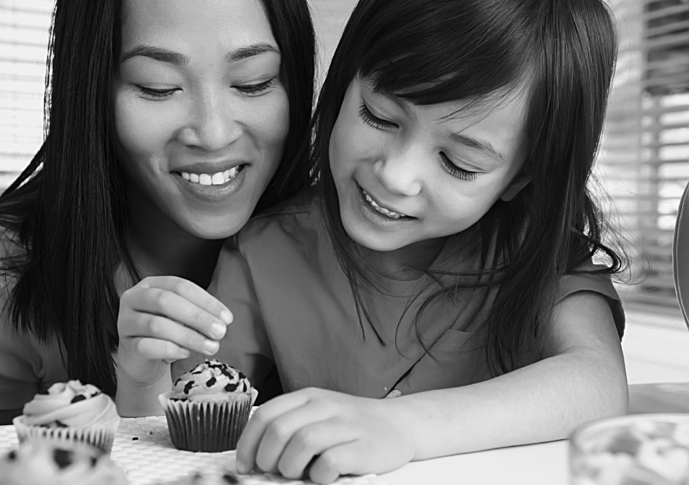 A photo shows an Asian mother and daughter decorating a cupcake.
