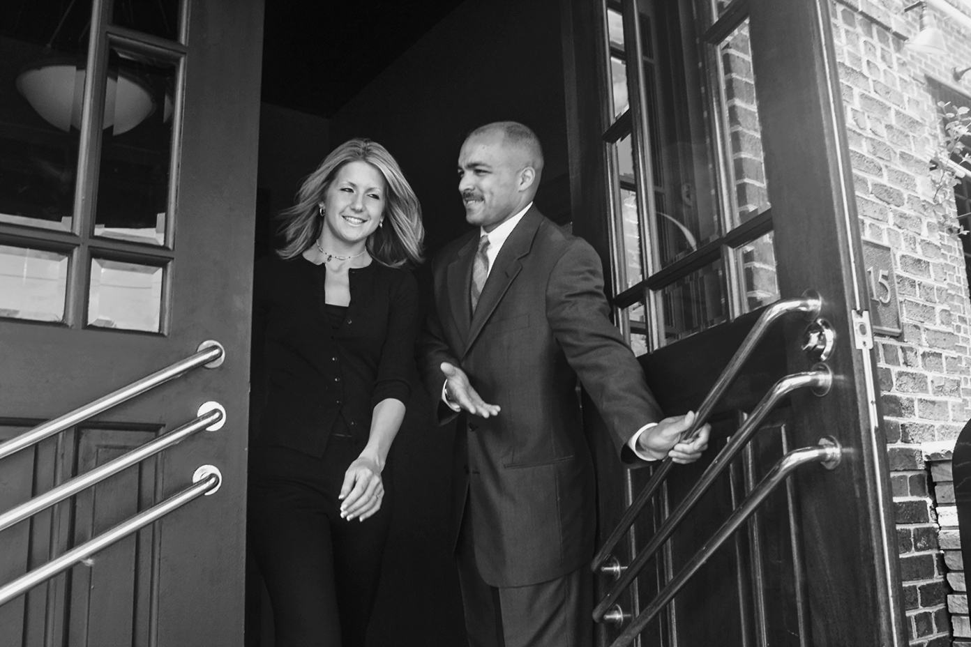 A photo shows a man holding a door open for a woman.