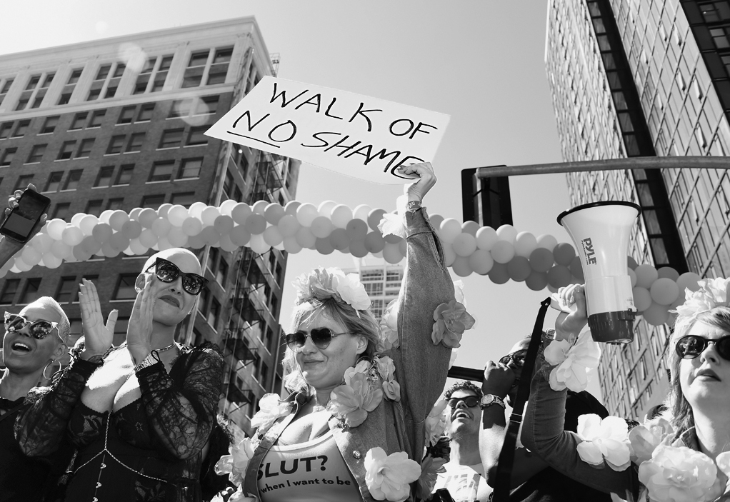 A photo shows model Amber Rose attending the Amber Rose Slutwalk. A woman standing next to her holds a placard that reads, “Walk of no shame.”
