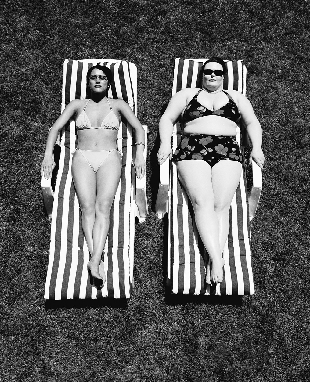 A photo shows a fat woman and a thin woman wearing bikinis and sunbathing.