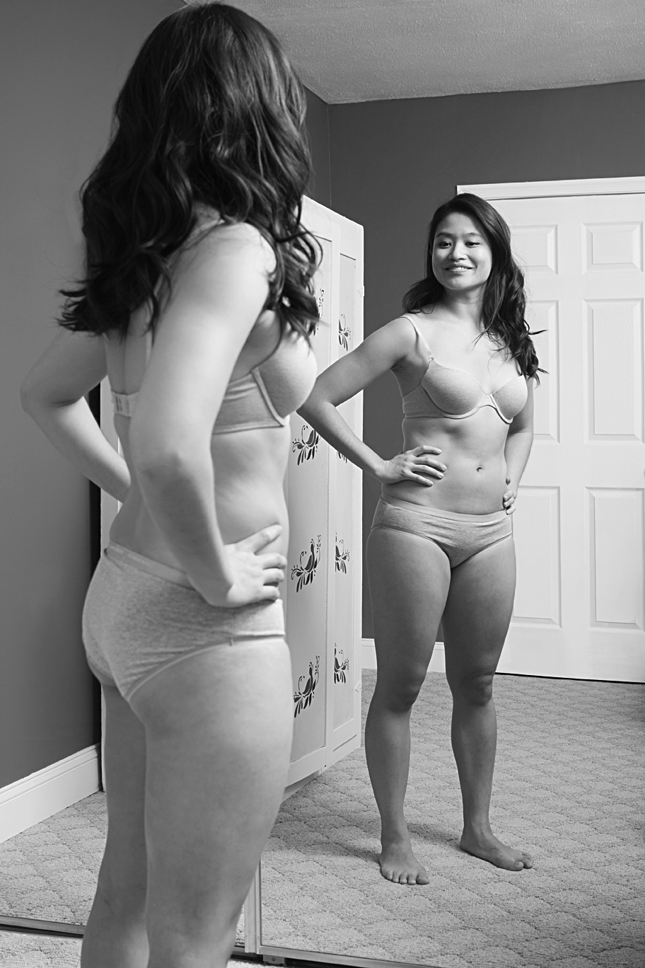 A photo shows a woman wearing underwear and smiling at herself in the mirror.