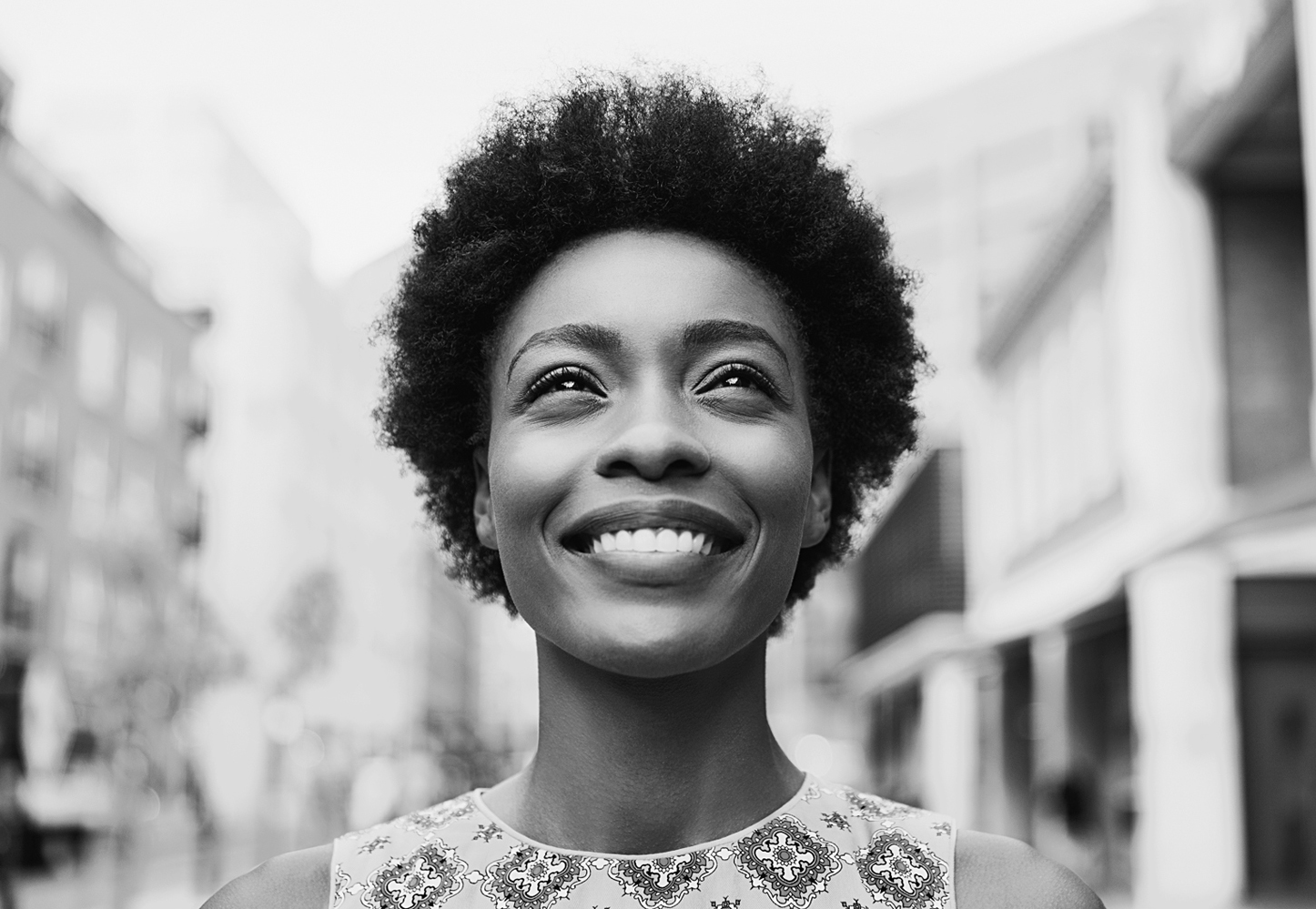 A photo shows a head shot of an African American woman with a dark skin tone and curly hair.
