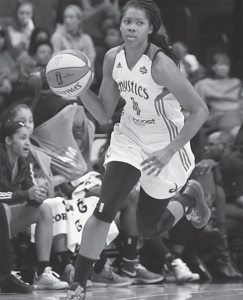 A photo shows a young woman dribbling during a basketball game.