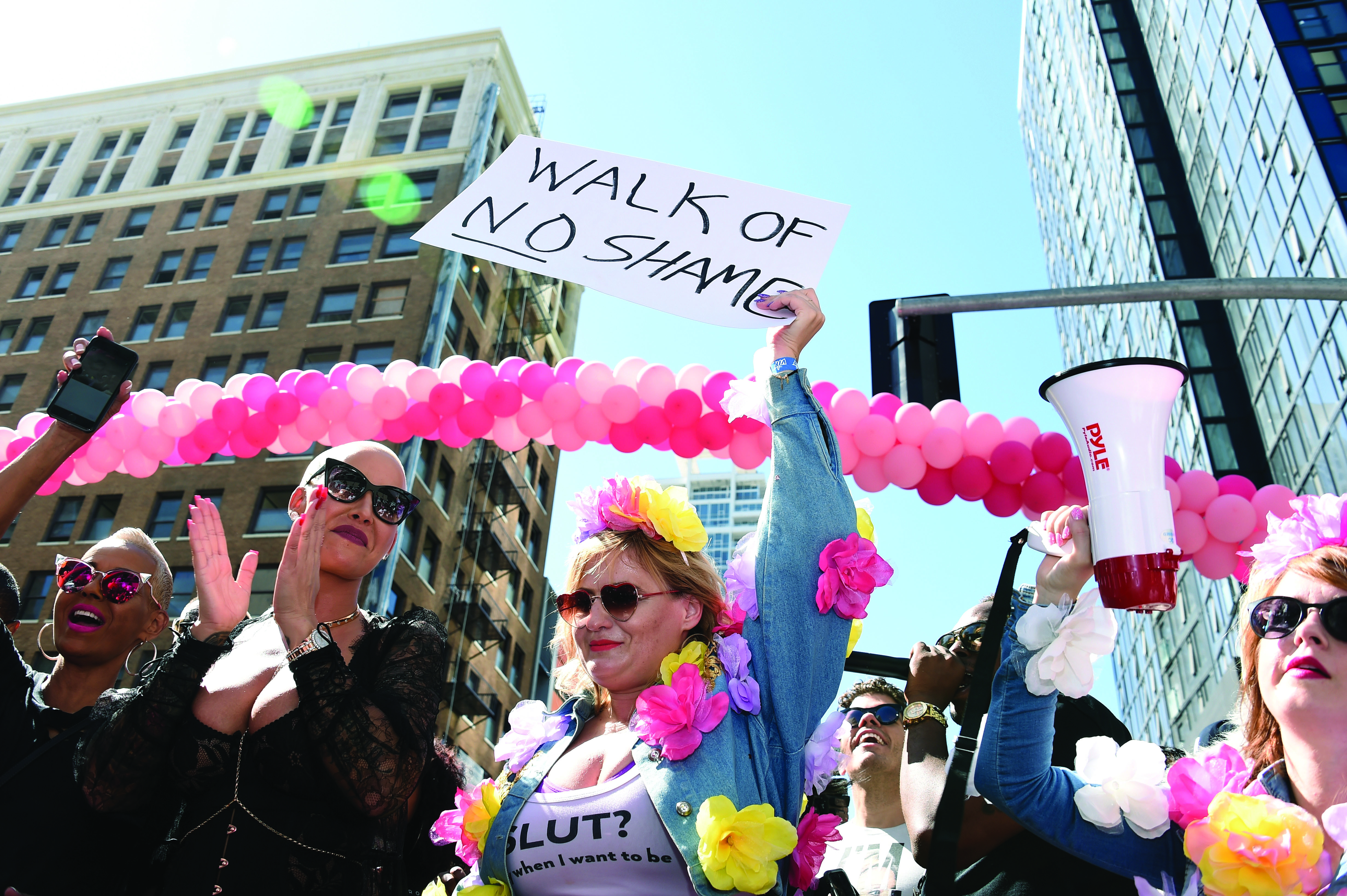 A photo shows women marching, one of whom holds a sign that reads, “Walk of no shame.”